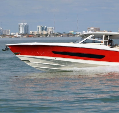 A large boat cruising at speed in front of a cityscape