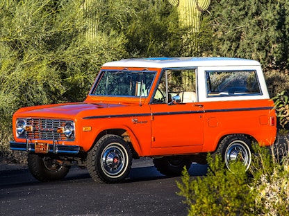 A red collector truck parked in front of cacti and desert brush