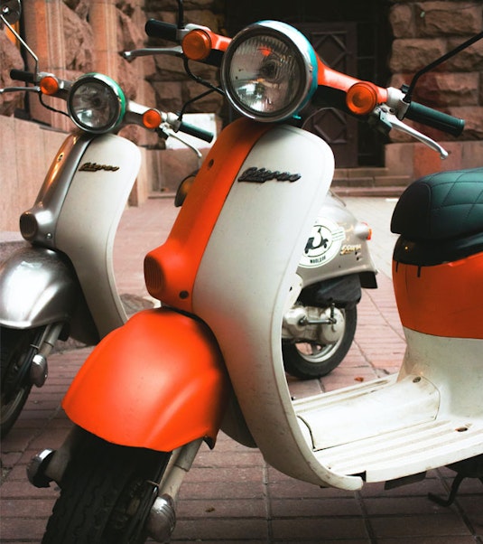 two vintage scooters parked side by side on street