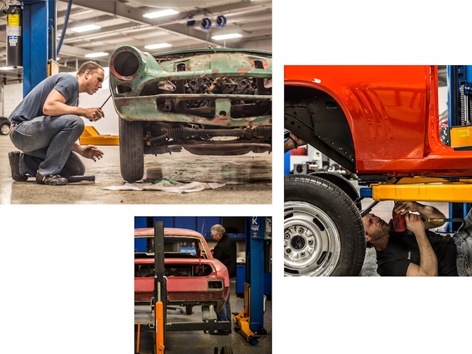 Vehicles being restored by men within a collector vehicle storage location.