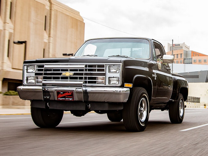 A black collector pickup truck driving on a city road