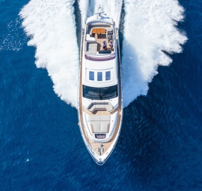 A white yacht pictured from above being directed through water.