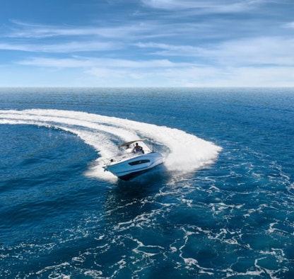 A white yacht pictured from the front being directed through water.