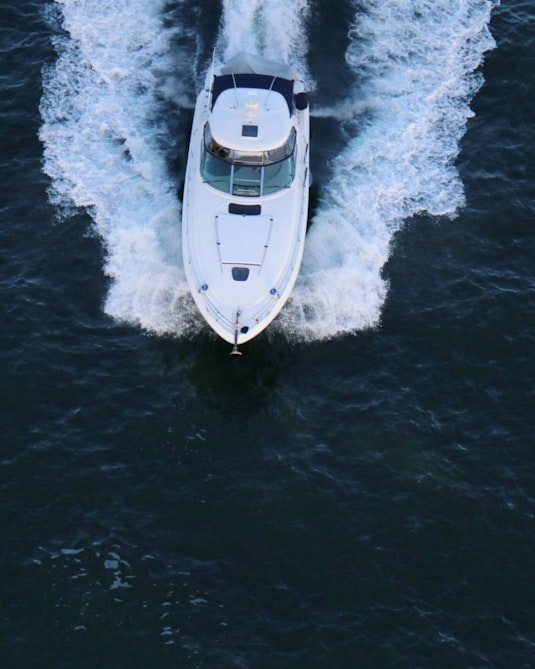 A white yacht pictured from above being directed through water.