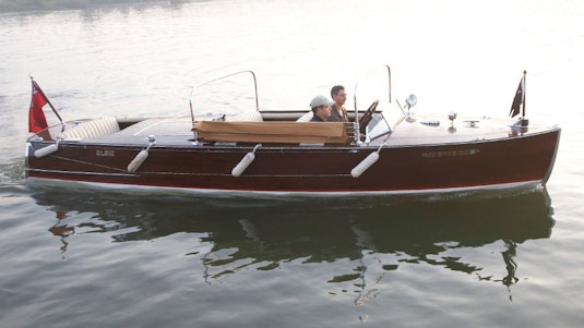 Two men directing a red collector boat through still water.