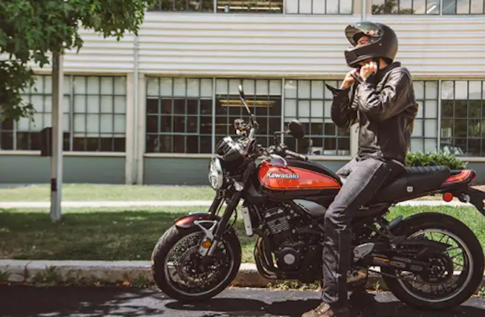 A man sits on a motorcycle outside of an office building